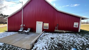 A red barn with a white door, two chairs outside, and a concrete porch. - Charming historic barn in New Market with WiFi and AC (New Market)