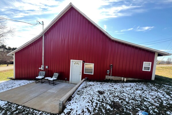 A red barn with a white door, two chairs outside, and a concrete porch. - Charming historic barn in New Market with WiFi and AC (New Market)