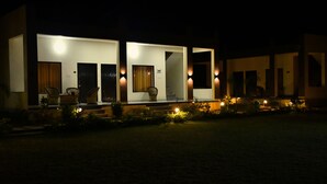 A modern building with multiple entry points, each illuminated by exterior lights. - Ranthambore Village Serai (Sawai Madhopur)