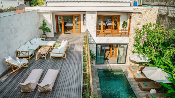 A modern house with a swimming pool, wooden deck, and outdoor seating area.