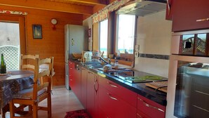 Een keuken met houten kasten, een roestvrijstalen koelkast en een eethoek met een tafel en stoelen.