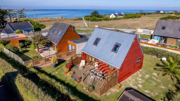 Een kustbezit met meerdere huizen, een houten terras en uitzicht op zee.