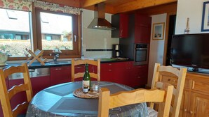 Een gezellige keuken met houten kastjes, een eettafel met tafelkleed en een televisie.