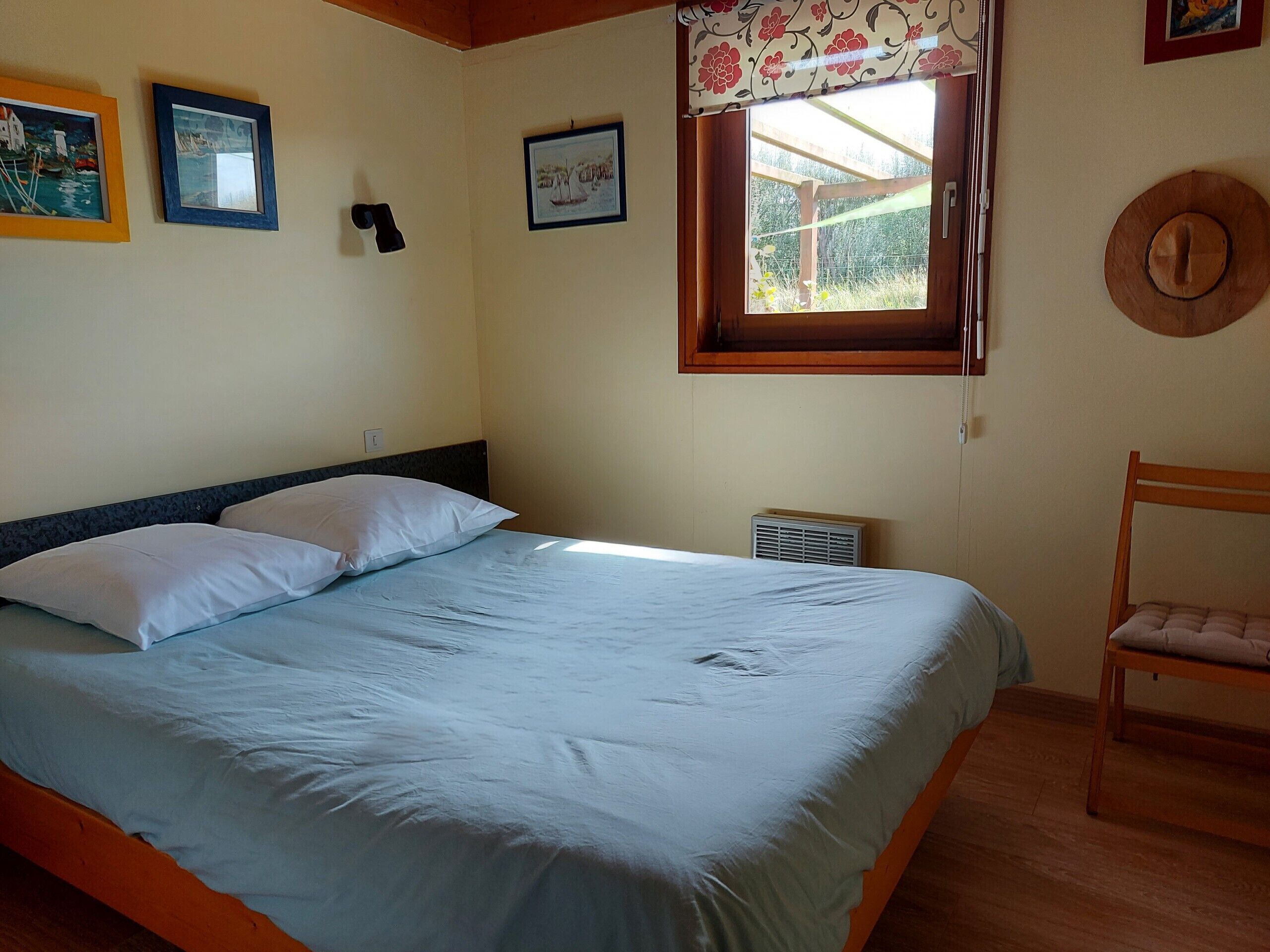 Une chambre à coucher avec un lit, une chaise et une fenêtre.
