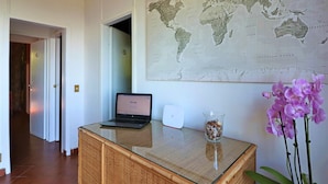 A hotel reception desk with a laptop, a world map, and a vase of flowers. - Villa Lalla (Sorrento)