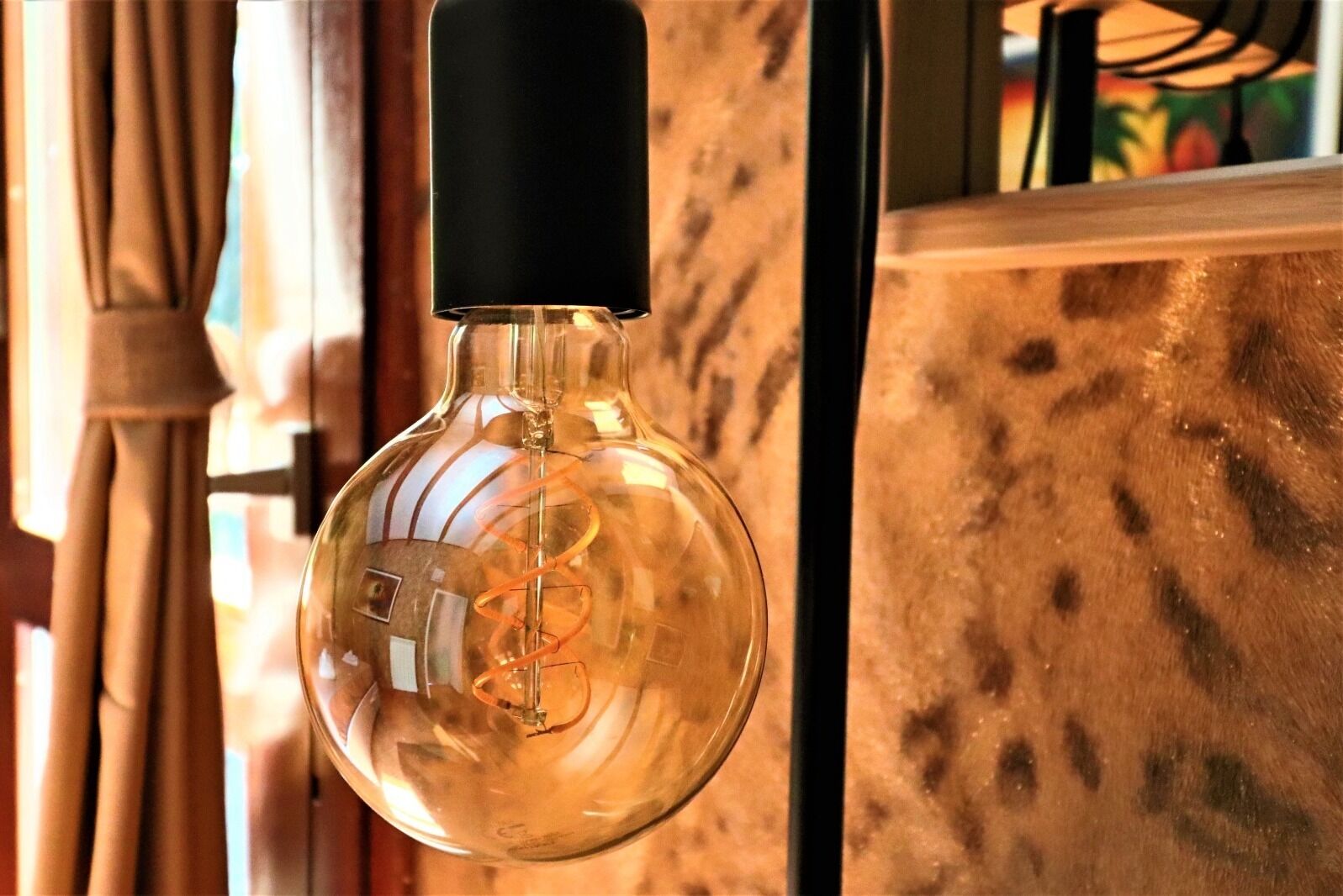 Un luminaire suspendu avec un socle noir et une ampoule en verre transparent au motif en spirale.