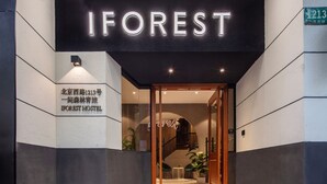 L’entrée de l’auberge IFOREST HOSTEL présente un design moderne, avec une porte en verre et une enseigne indiquant le nom de l’auberge.
