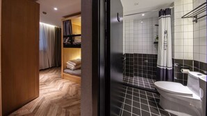 Une salle de bain moderne avec un carrelage noir et blanc, des toilettes blanches et un espace douche séparé par un rideau.