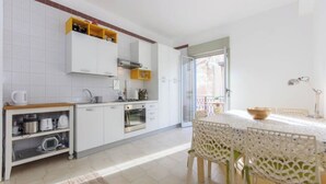 A modern kitchen with white cabinets, a built-in oven, and a dining area with a white table and chairs.