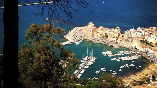 A coastal town with a marina, historic buildings, and a clear view of the sea.