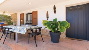 An outdoor patio with a table and chairs, a potted plant, and a door with a decorative panel.