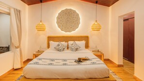 Ein ordentlich eingerichtetes Schlafzimmer mit einem großen Bett, zwei Nachttischen, einer Wanddekoration und zwei Hängeleuchten.
