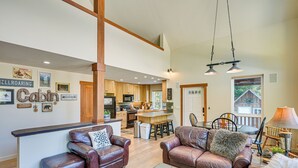 Ein geräumiges Wohnzimmer mit Ledersofas, einem Couchtisch mit dekorativen Steinen und einer Küche im Hintergrund.