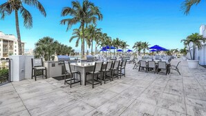 Un patio al aire libre con una parrilla, asientos y palmeras.