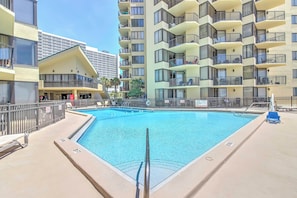 A swimming pool surrounded by a high-rise building with balconies and a modern architectural design. - Gulf-view Balcony: Beachfront Condo in Pcb! (Panama City Beach)