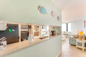 A modern kitchen with a granite countertop, stainless steel appliances, and a dining area with a white table and chairs.