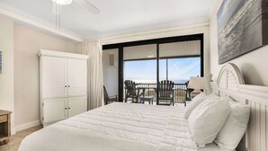 A bedroom with a large bed, a chair, a table, and a view of the ocean. - Grand Pointe 411, 3 bedrooms, 3 and a half baths, DIRECT BEACH FRONT (Orange Beach)