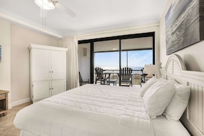 A bedroom with a large bed, a chair, a table, and a view of the ocean. - Grand Pointe 411, 3 bedrooms, 3 and a half baths, DIRECT BEACH FRONT (Orange Beach)