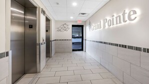 A clean, modern hallway with a 'Grand Pointe' sign, elevators, and a tiled floor. - Grand Pointe 411, 3 bedrooms, 3 and a half baths, DIRECT BEACH FRONT (Orange Beach)