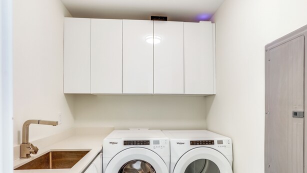 A laundry room with two front-loading washers, a sink, and white cabinets. - Condo at Amrit Ocean Resort w/ Panoramic Views (Singer Island)