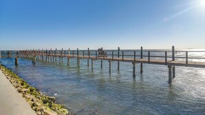 A pier extending into calm waters with a clear sky above.