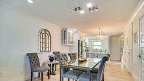 A modern kitchen with a central island, built-in appliances, and a dining area with a glass table and upholstered chairs.