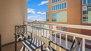 A balcony with a view of a pool and a building with multiple windows.