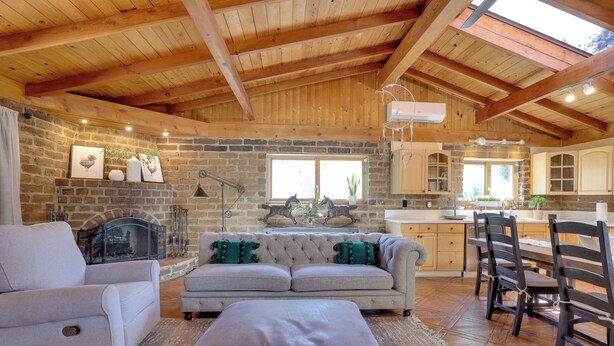 A spacious living room with a fireplace, a sofa, and a dining area with chairs. - 4 Mi to Lake Wohlford: Cabin in Escondido (Valley Center)