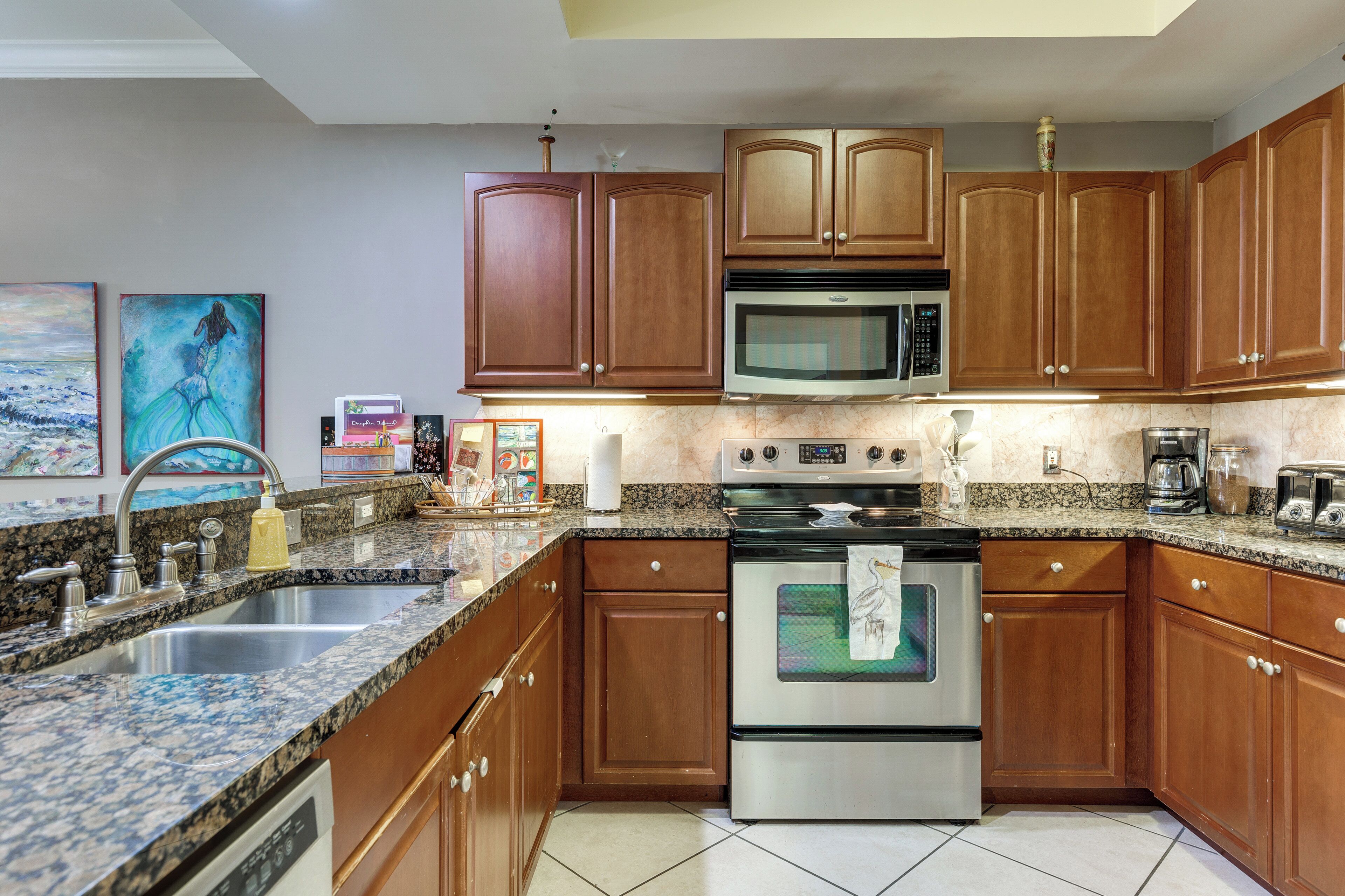 A kitchen with granite countertops, stainless steel appliances, wooden cabinets, and a microwave above the stove.