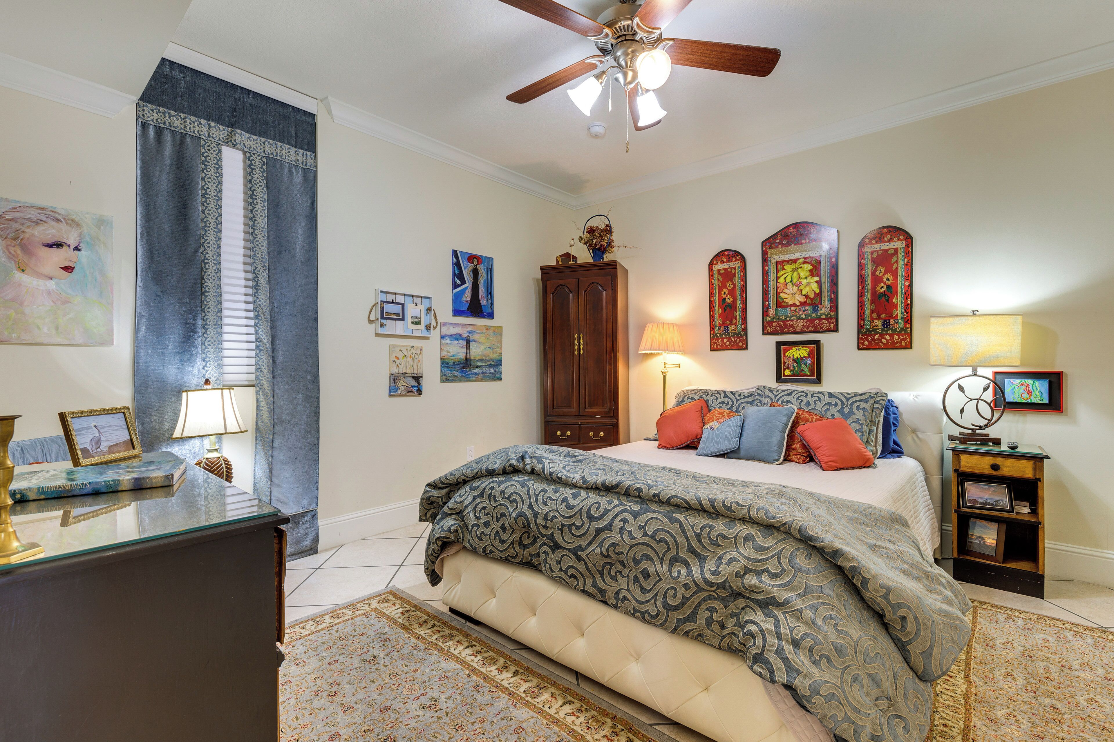 A bedroom with a bed, a ceiling fan, a nightstand, and wall decorations.