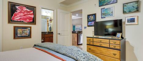 A bedroom with a bed, dresser, and artwork on the walls.