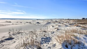 A sandy beach with sparse vegetation and a clear blue sky.