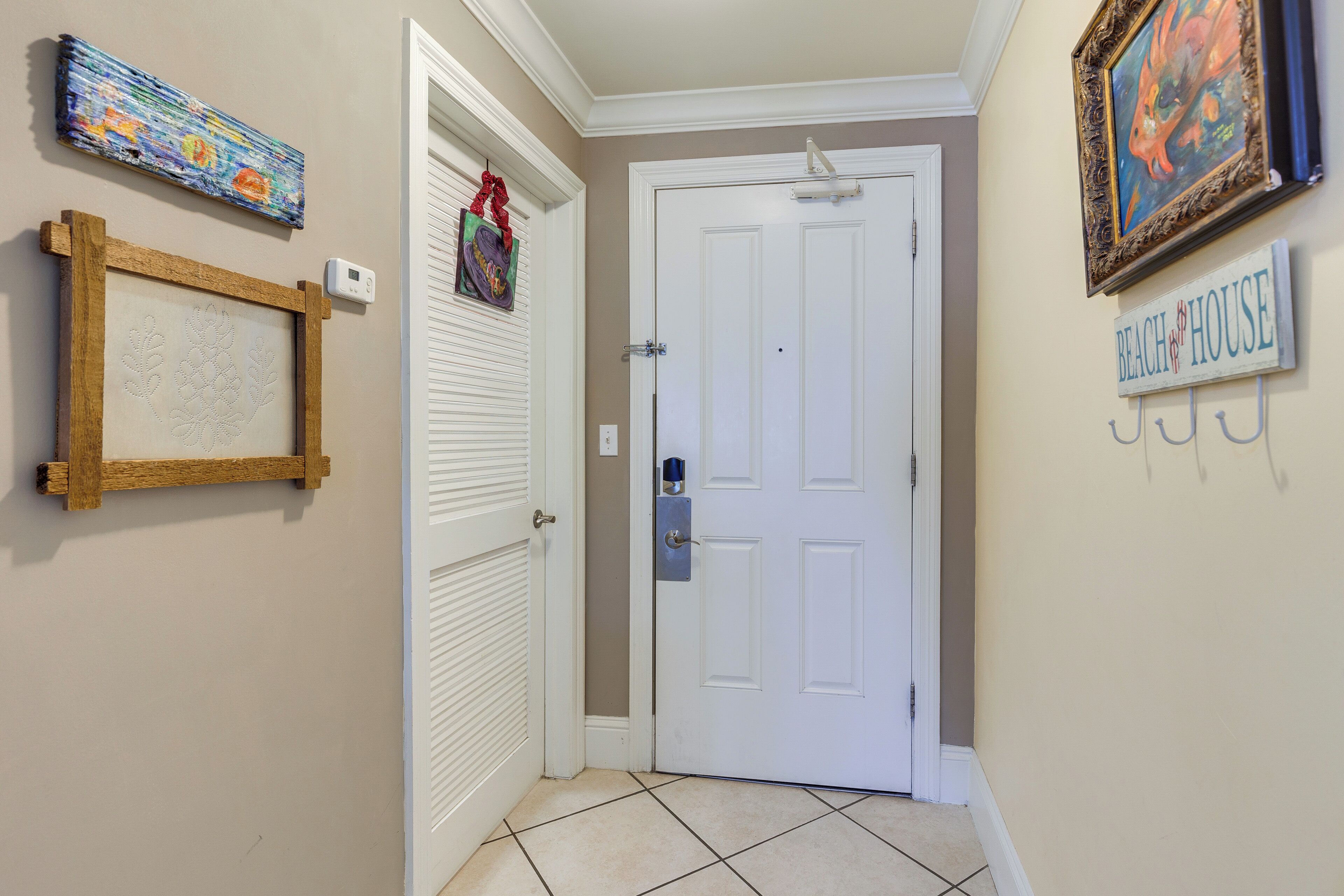 A hallway with a white door, a framed picture, a small sign, and a wall-mounted light fixture.