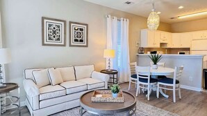 A modern living room with a sofa, coffee table, and dining area. - River Oaks 2BR beautiful condo (Myrtle Beach)