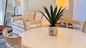 A dining area with a round table, chairs, a potted plant, and a hanging light fixture. - River Oaks 2BR beautiful condo (Myrtle Beach)