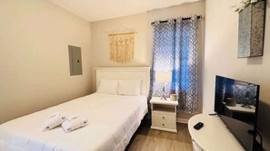 A hotel room with a bed, bedside table, lamp, and a TV. - River Oaks 2BR beautiful condo (Myrtle Beach)
