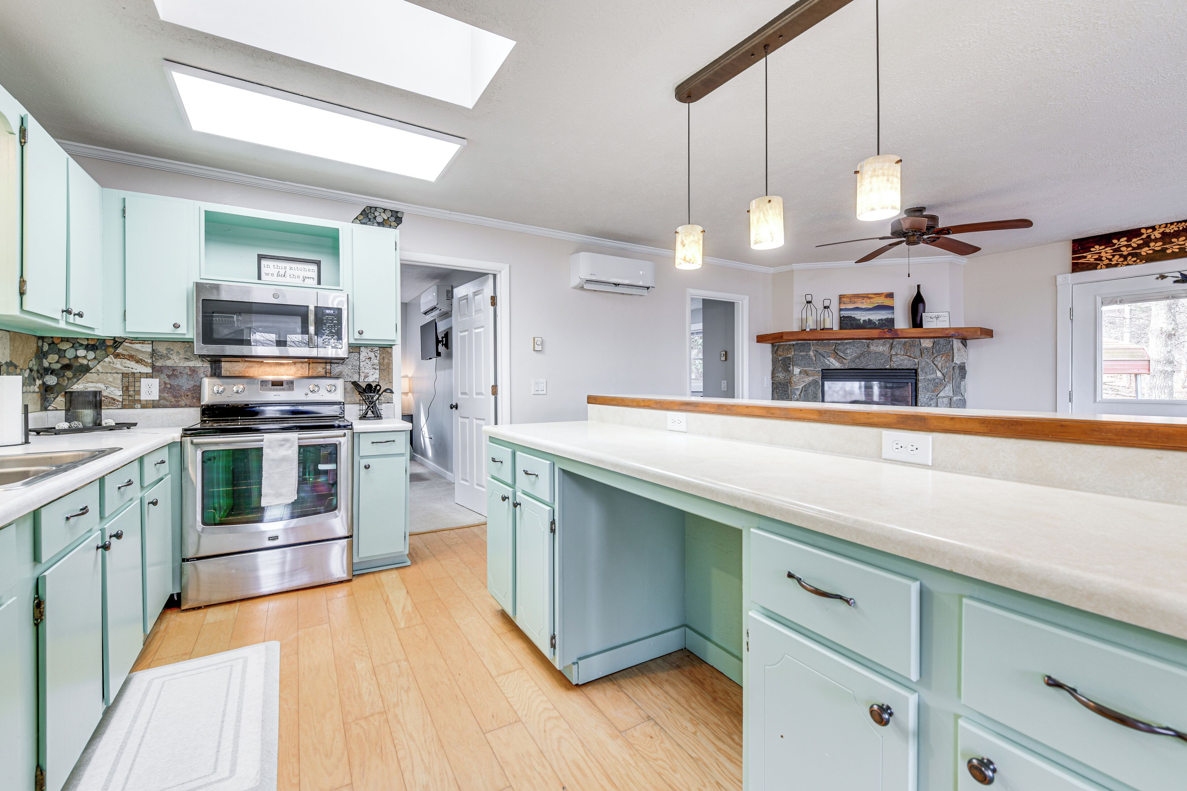 A kitchen with light blue cabinets, a central island, a built-in oven, and a ceiling fan.
