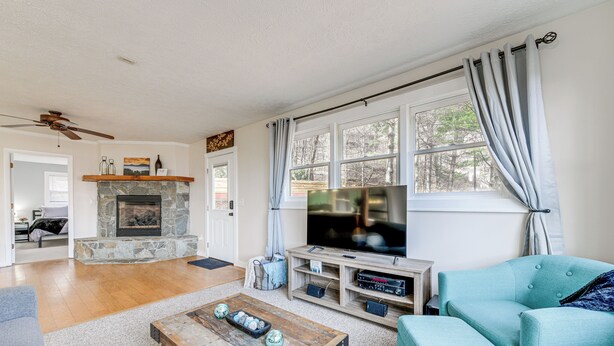 Una sala de estar con chimenea de piedra, televisor, sofá y mesa de centro.