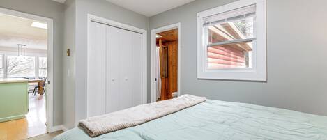 Une chambre à coucher avec un lit, une fenêtre et une porte donnant sur une autre pièce.