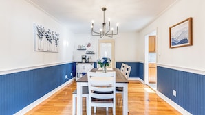 A dining area with a wooden table and white chairs, a chandelier, and a vase of flowers. - 3 Mi to Hospitals: Inviting Rockford Home w/ Yard! (Rockford)