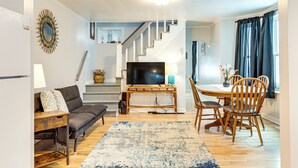 Una sala de estar con sofá, mesa de centro, televisor y zona de comedor con sillas y una mesa.