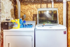 A laundry area with a washing machine and dryer, a water heater, and various cleaning supplies on the counter. - 4 Mi to Lake Superior: Calumet Getaway! (Calumet)