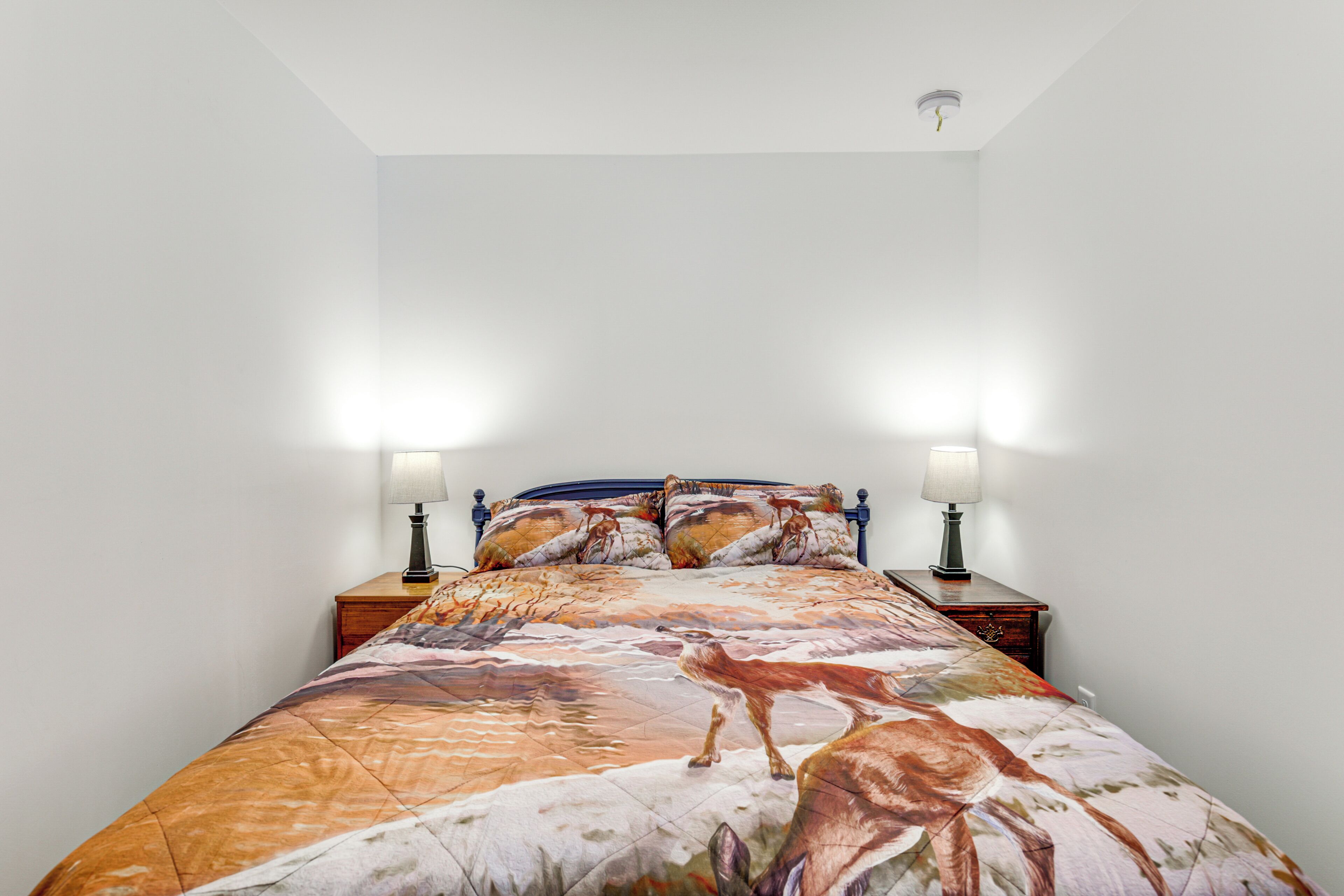 A bedroom with a bed, two bedside lamps, and a nightstand.