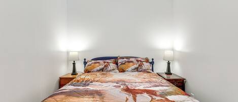 A bedroom with a bed, two bedside lamps, and a nightstand.