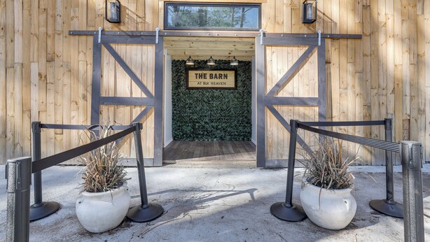 A wooden barn entrance with a sign reading "The Barn at BLK Heaven" and a gated pathway with potted plants. - Georgia Farmhouse Studio w/ Hiking Trail (Lithonia)