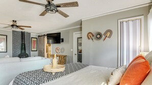 A bedroom with a bed, two ceiling fans, a TV, and a door with decorative items. - Georgia Farmhouse Studio w/ Hiking Trail (Lithonia)