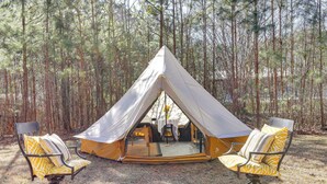 A tent with a dining table and two chairs in a forest setting. - Georgia Farmhouse Studio w/ Hiking Trail (Lithonia)