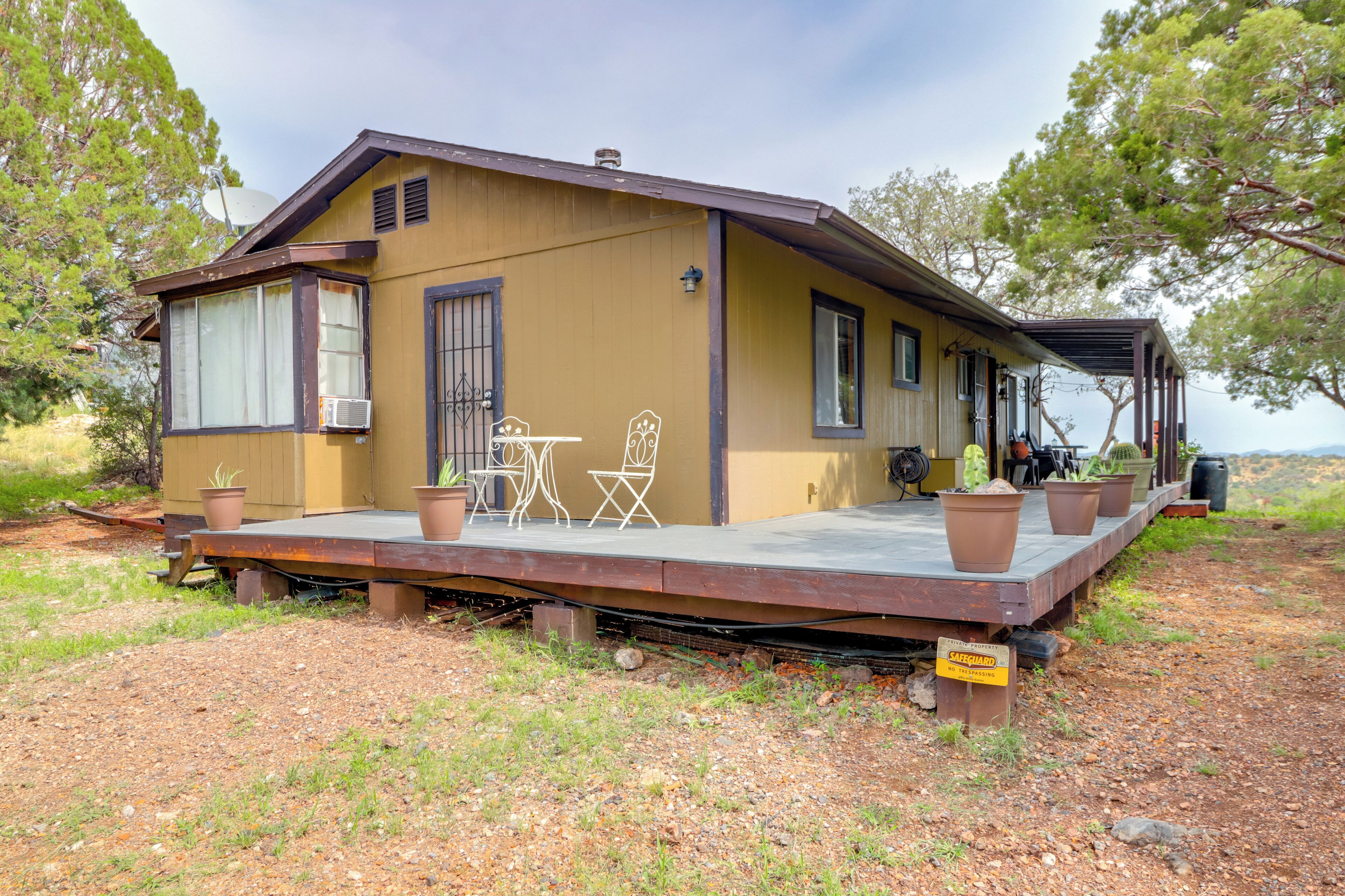 Una casa de una sola planta con un patio, mobiliario exterior y plantas en macetas.