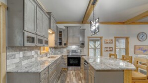 A kitchen with grey cabinets, a central island, and a built-in oven. - Greers Ferry Lake Access & Deck: Group Getaway! (Drasco)