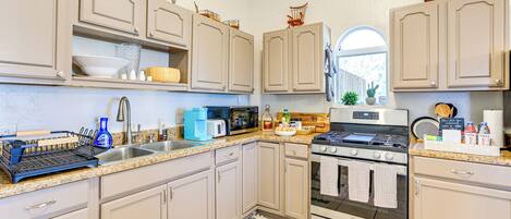 A kitchen with beige cabinets, stainless steel appliances, and a granite countertop.